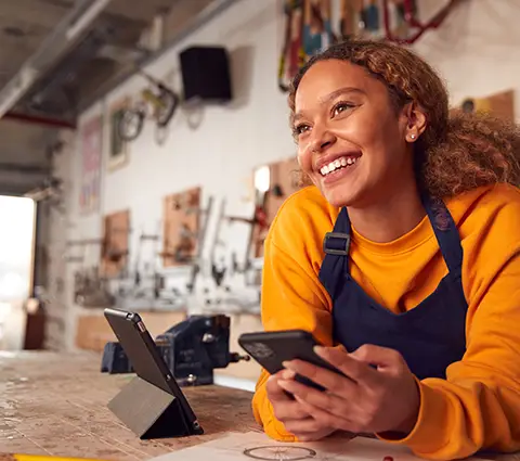 Happy female business owner in her workshop holding her phone