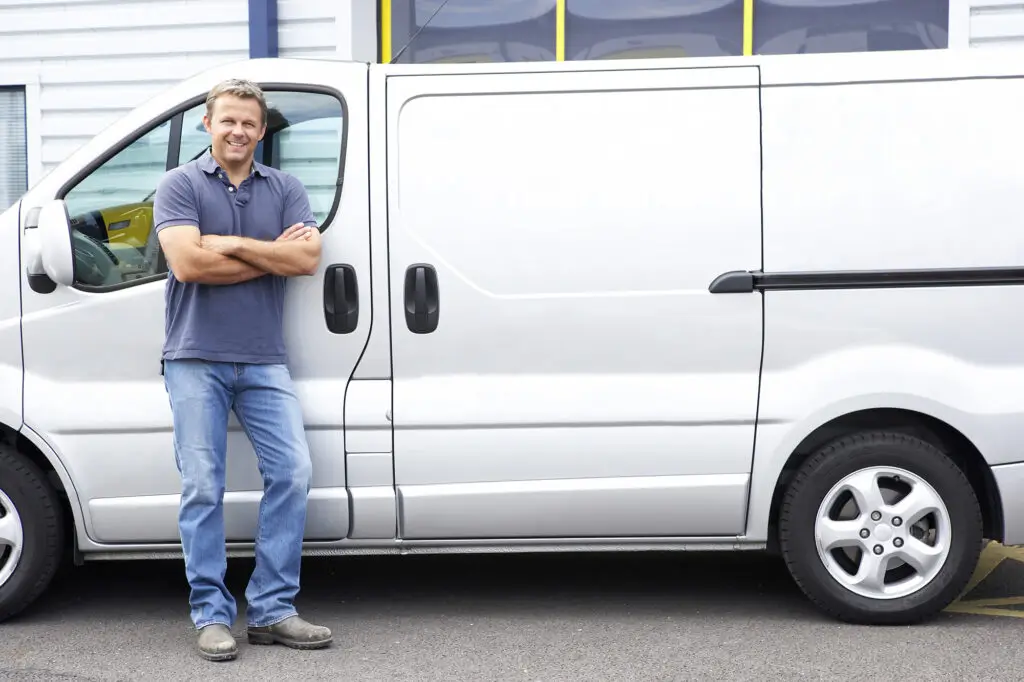 A male worker / tradie standing by his work van