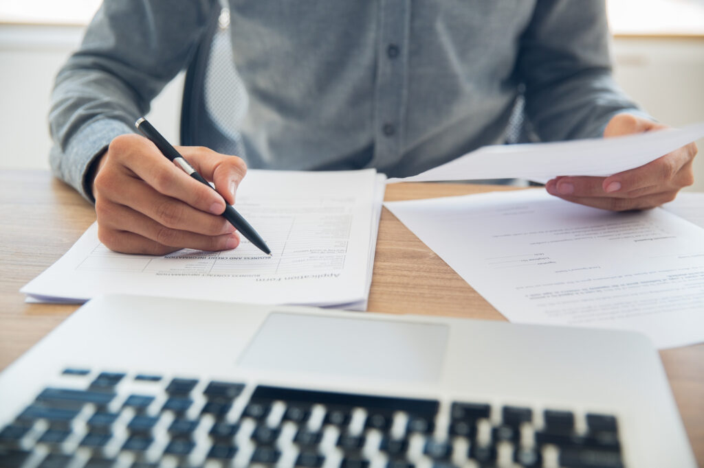 Man going through his paperwork deciding whether he should refinance his loan or not