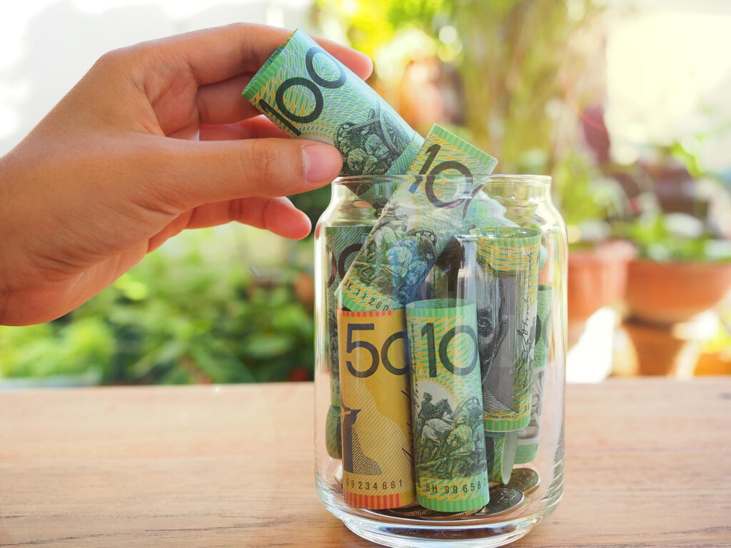 Someone putting money in a jar to save for their first house