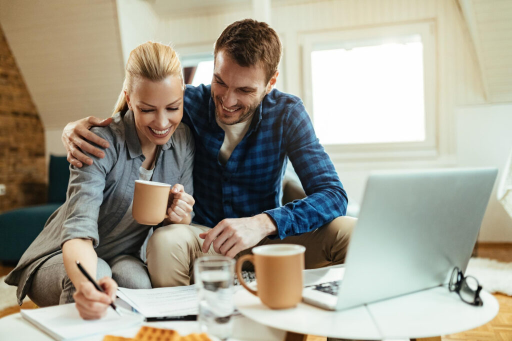 A happy couple going through paperwork, drinking coffee