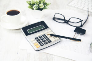 A person working out their borrowing power with a calculator on their desk with glasses and a coffee
