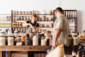 A female business owner working in her health food shop, serving a customer