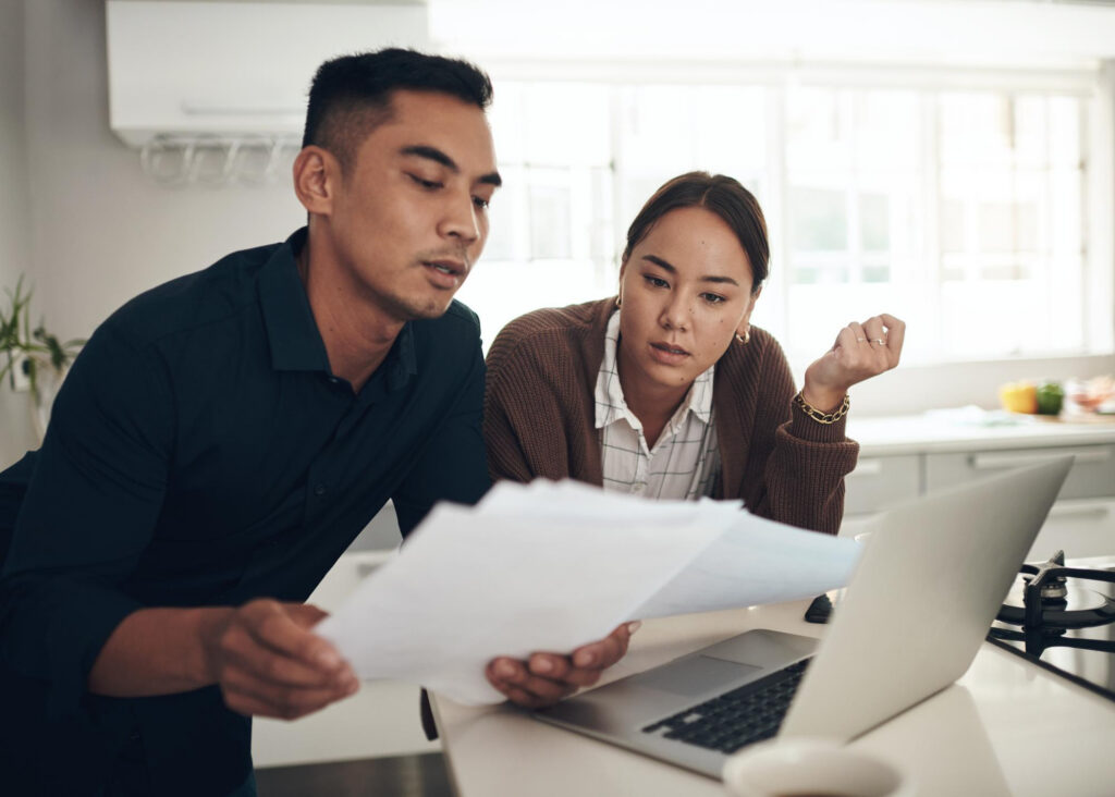 Young couple looking at paperwork, deciding if a broker or a bank is better for them