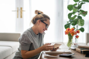 A woman on the phone working out her finances with a calculator